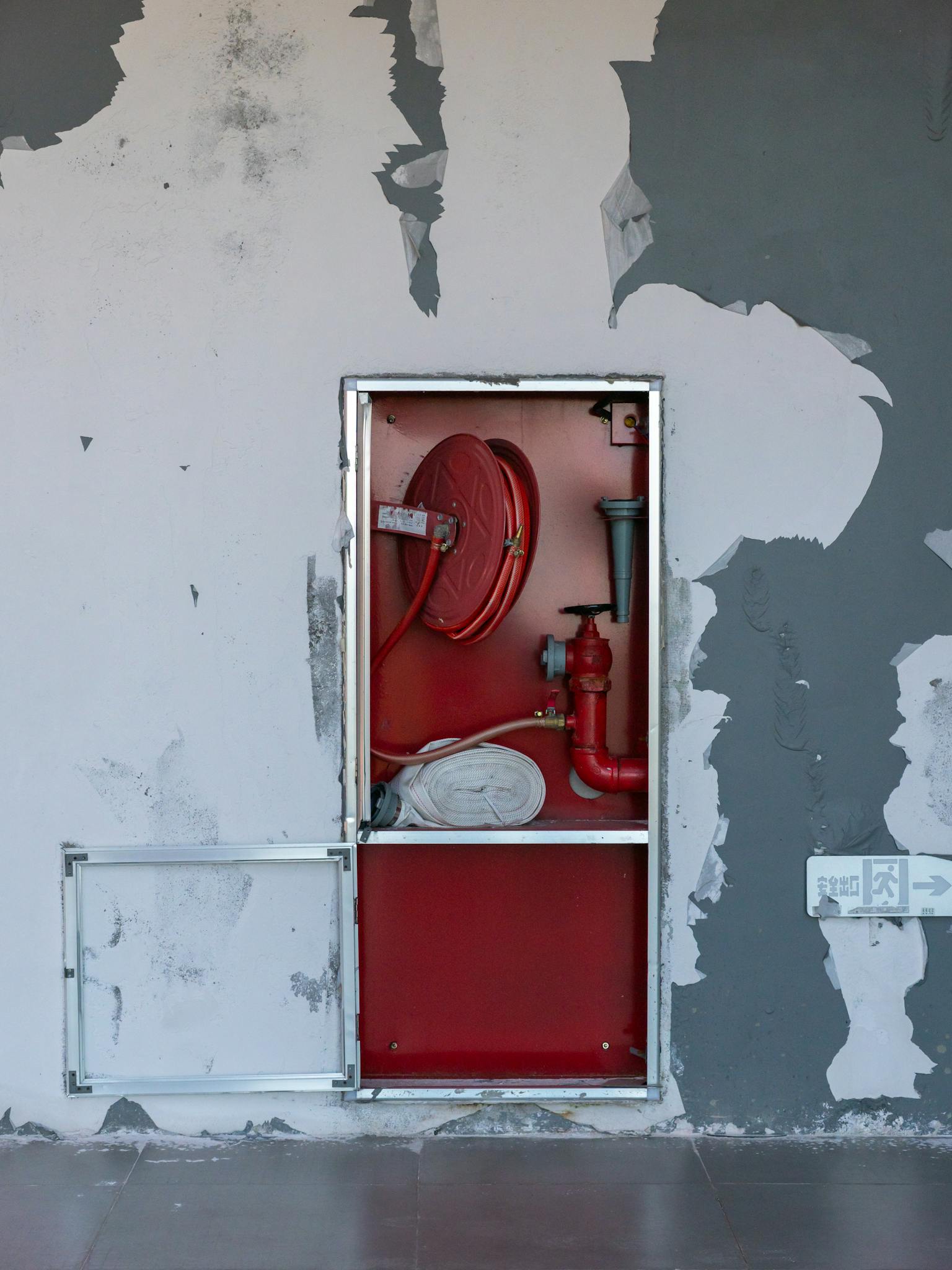 An exposed fire safety equipment installed on a peeling wall indoors.