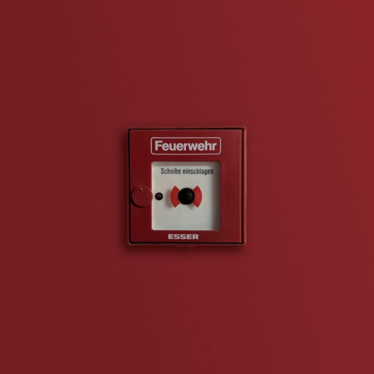 Red fire alarm panel indicating emergency system on solid background.
